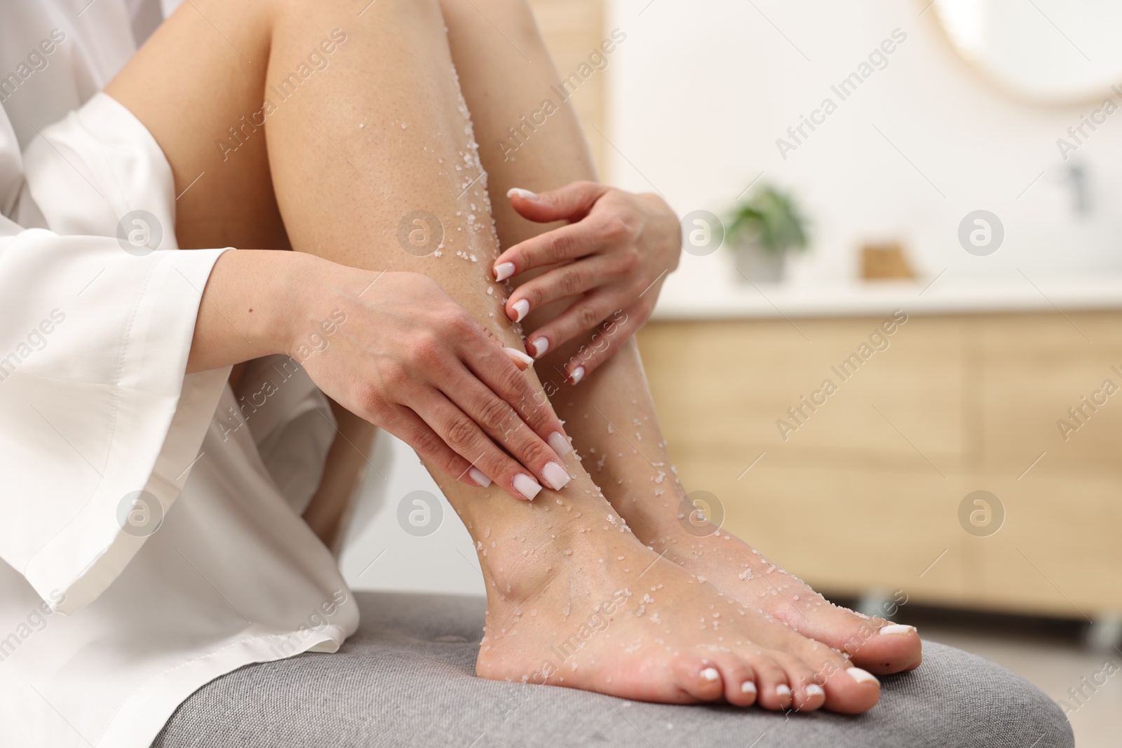 Woman applying body scrub onto her leg indoors, closeup Photo of Woman applying body scrub onto her leg indoors, closeup