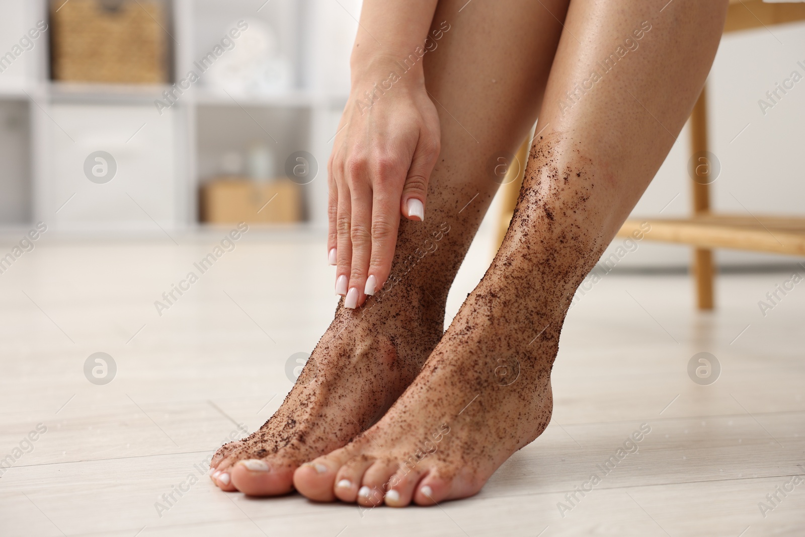 Woman applying body scrub onto her feet indoors, closeup Photo of Woman applying body scrub onto her feet indoors, closeup