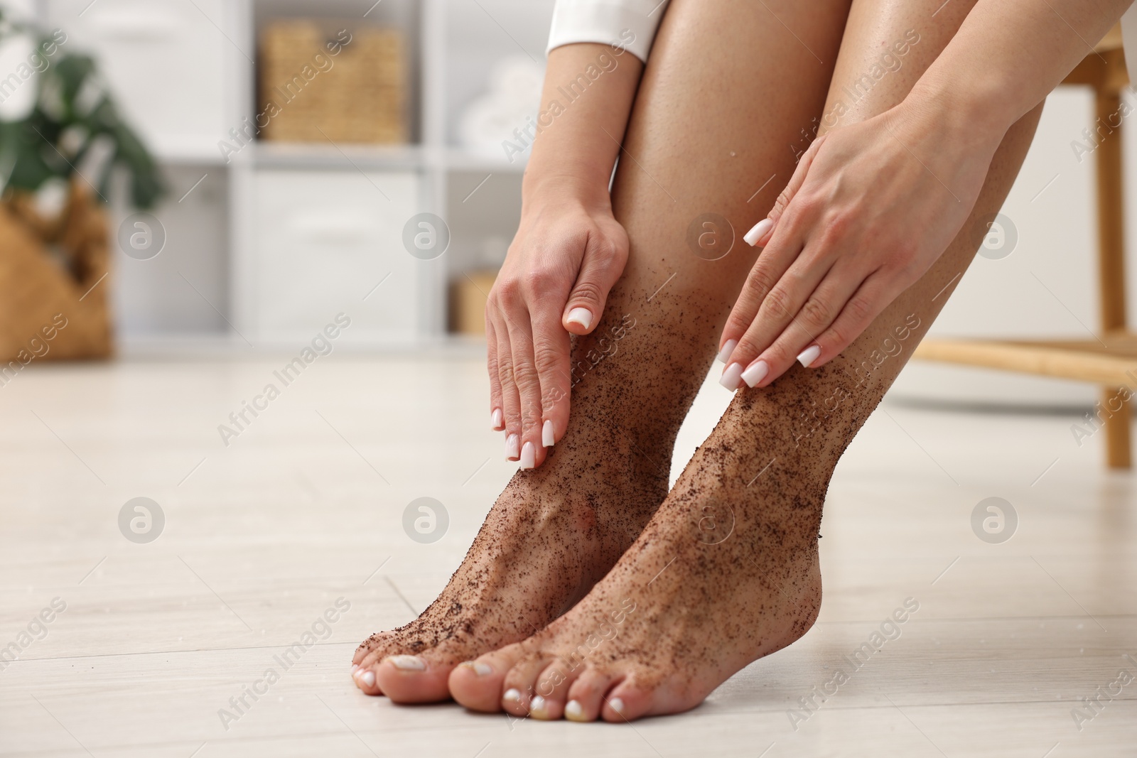 Woman applying body scrub onto her feet indoors, closeup. Space for text Photo of Woman applying body scrub onto her feet indoors, closeup. Space for text