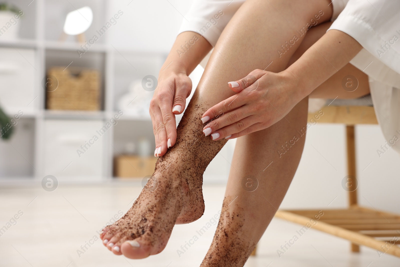 Woman applying body scrub onto her leg indoors, closeup Photo of Woman applying body scrub onto her leg indoors, closeup