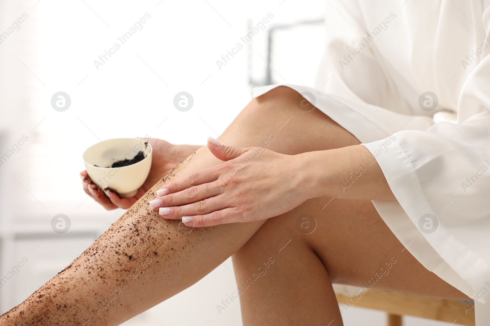 Woman applying body scrub onto her leg indoors, closeup Photo of Woman applying body scrub onto her leg indoors, closeup