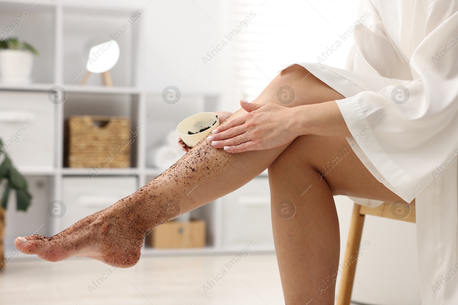 Woman applying body scrub onto her leg indoors, closeup Photo of Woman applying body scrub onto her leg indoors, closeup
