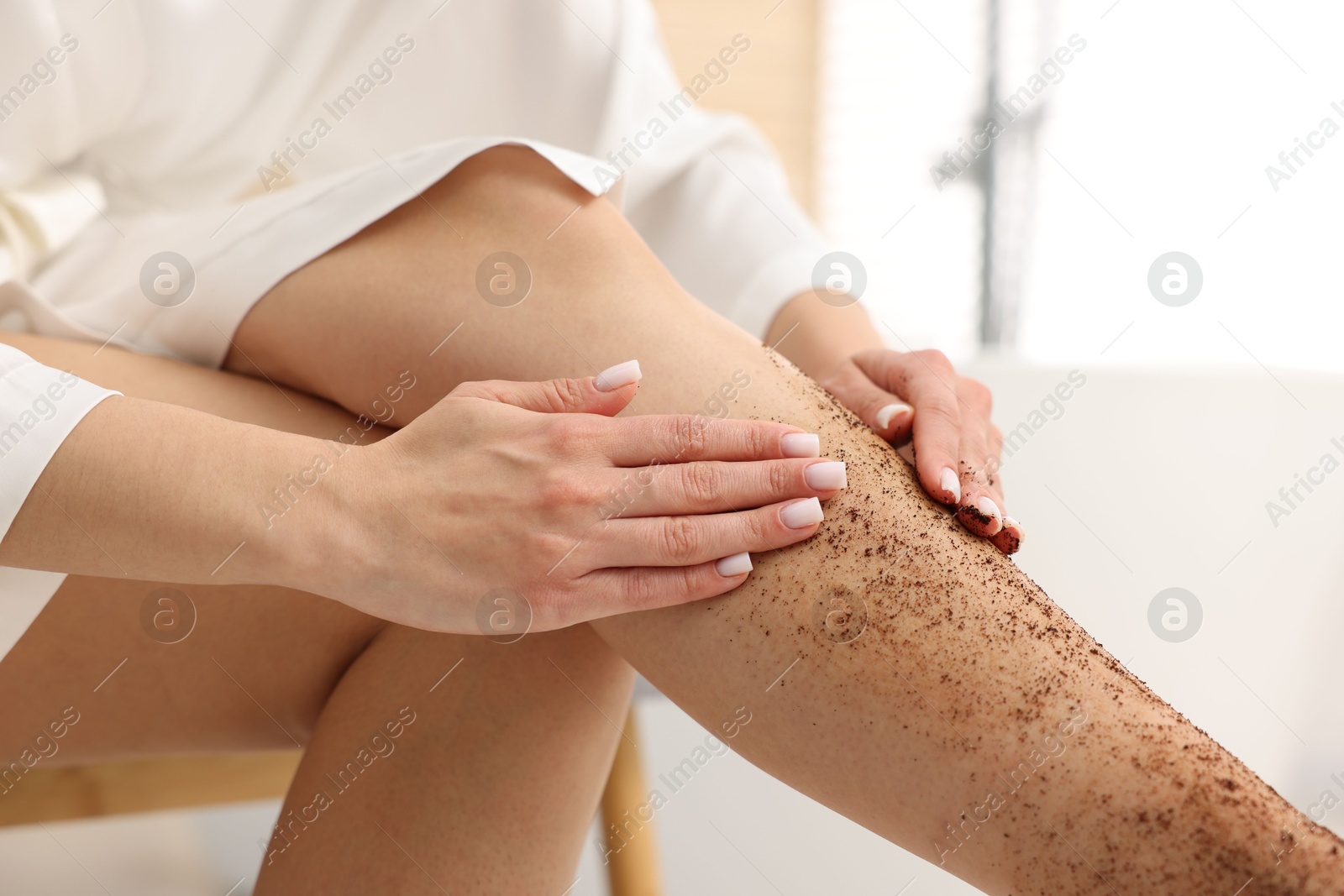 Woman applying body scrub onto her leg indoors, closeup Photo of Woman applying body scrub onto her leg indoors, closeup