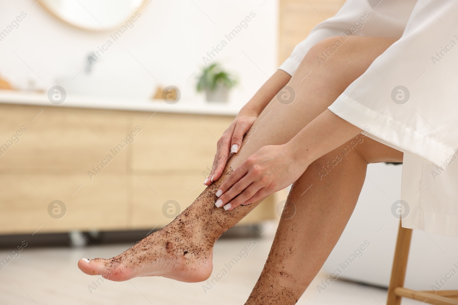 Woman applying body scrub onto her leg indoors, closeup Photo of Woman applying body scrub onto her leg indoors, closeup