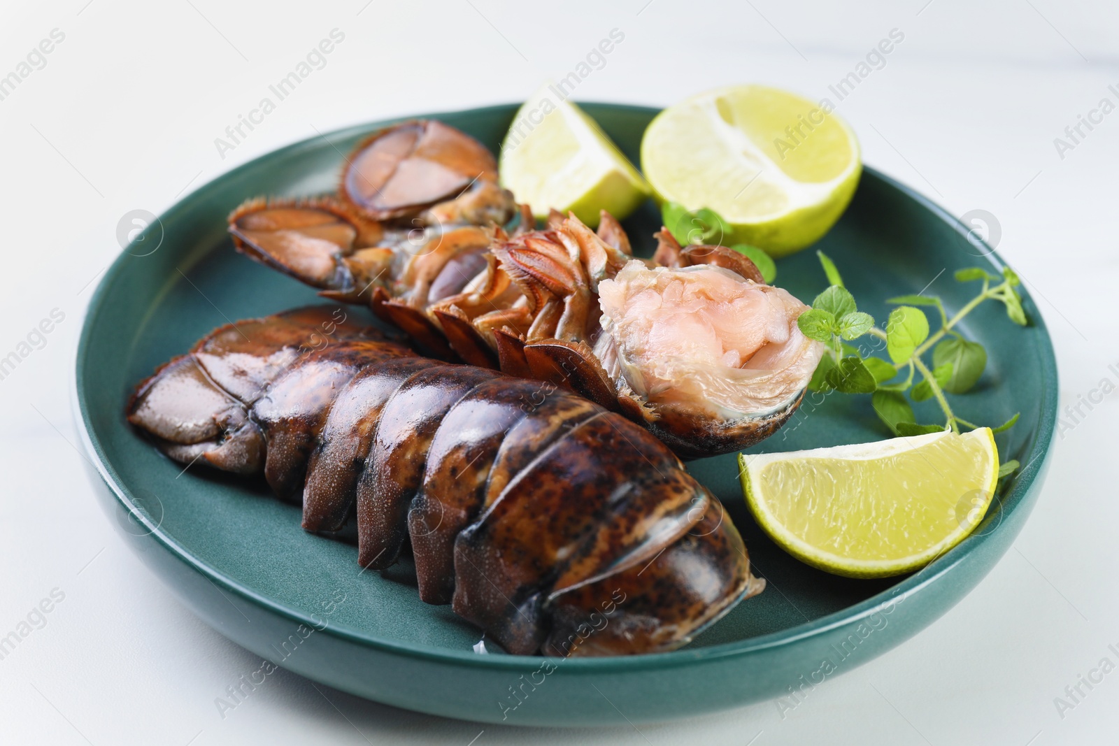 Raw lobster tails, lime and microgreens on white table, closeup Photo of Raw lobster tails, lime and microgreens on white table, closeup