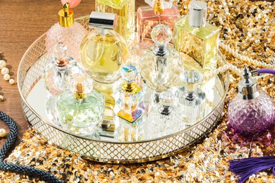 Photo of Different luxury perfumes and accessories on wooden table