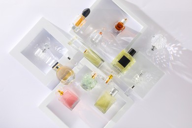 Photo of Different luxury perfumes on white background, flat lay