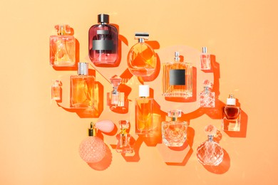 Photo of Different luxury perfumes on beige background, flat lay