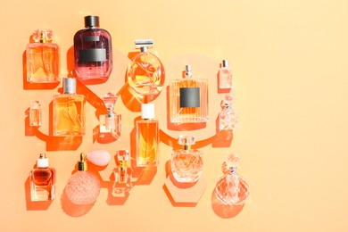 Photo of Different luxury perfumes on beige background, flat lay. Space for text