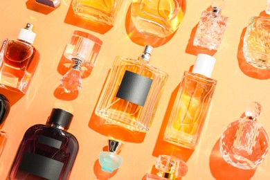 Photo of Different luxury perfumes on beige background, flat lay