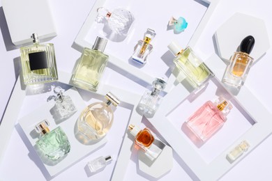 Photo of Different luxury perfumes on white background, flat lay