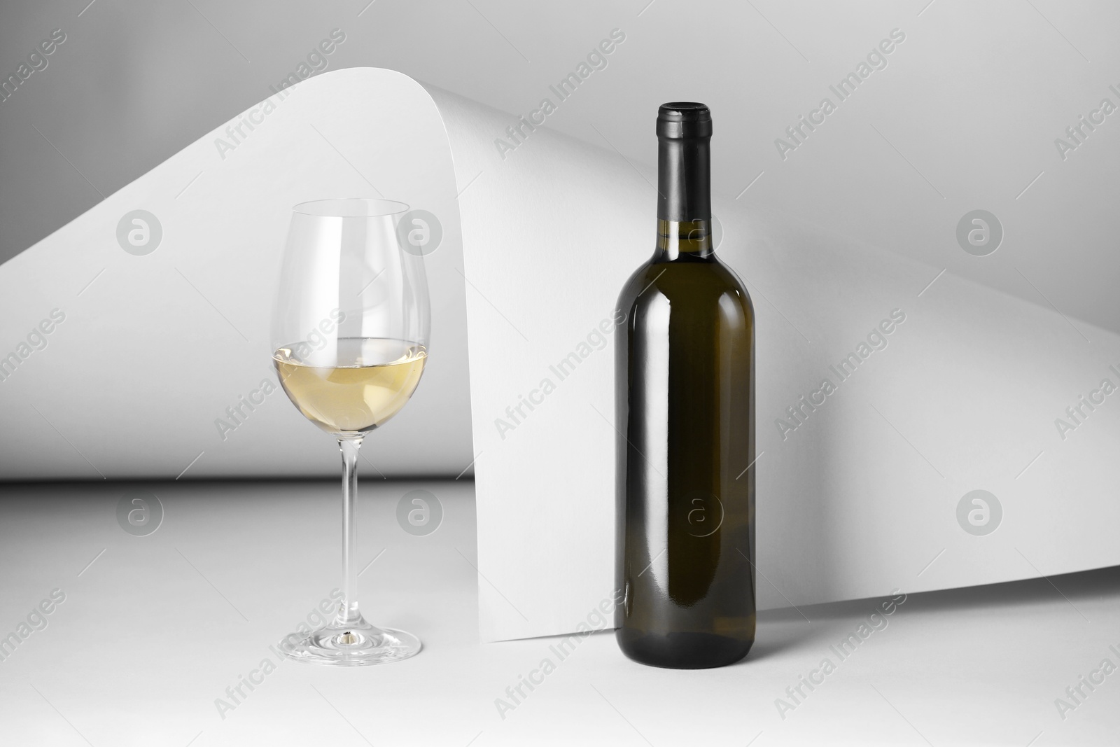 Bottle and glass of tasty wine on light grey background Photo of Bottle and glass of tasty wine on light grey background
