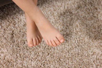Photo of Little child above soft beige carpet indoors, closeup. Space for text