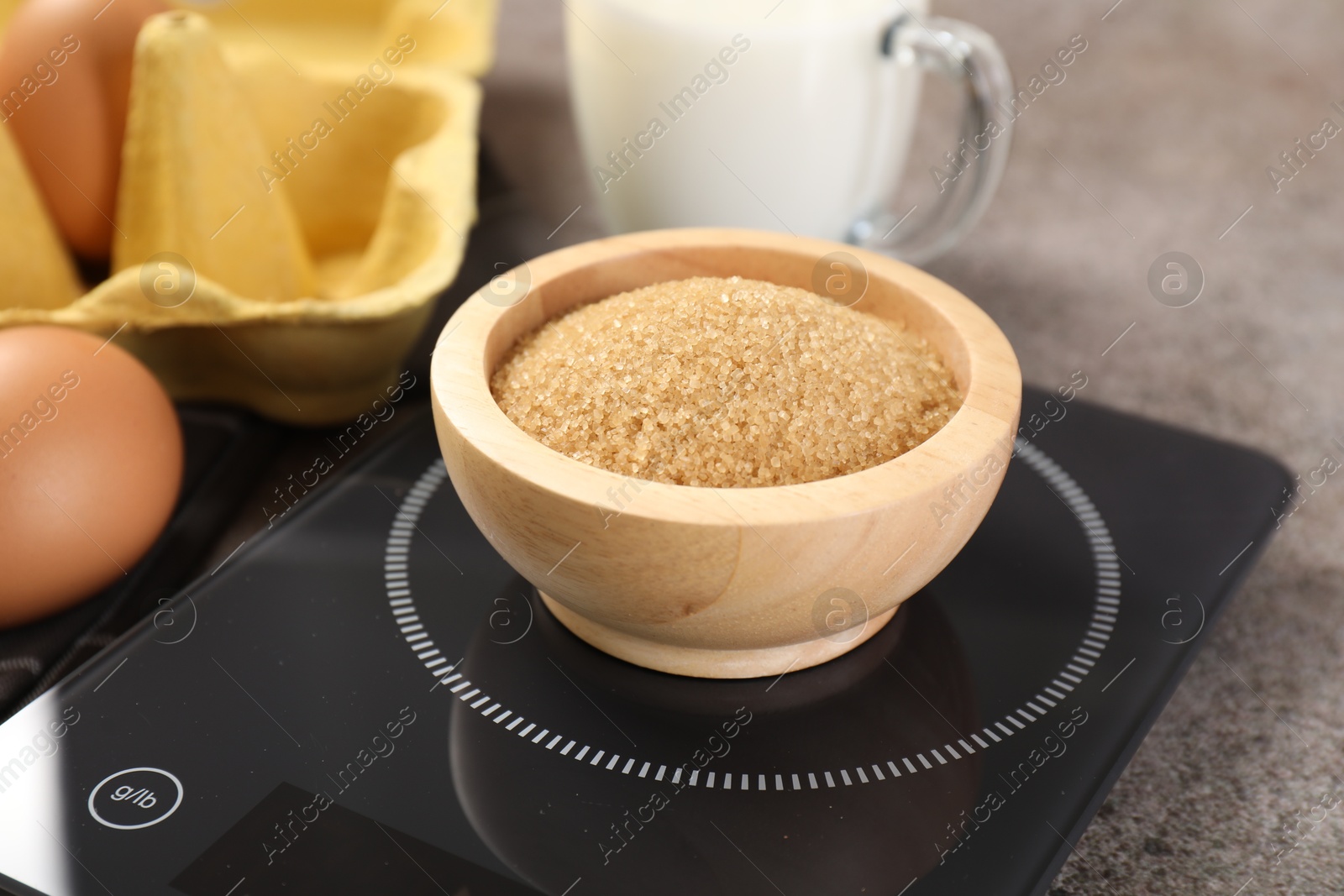Digital kitchen scale with bowl of brown sugar and other products on grey table, closeup Photo of Digital kitchen scale with bowl of brown sugar and other products on grey table, closeup