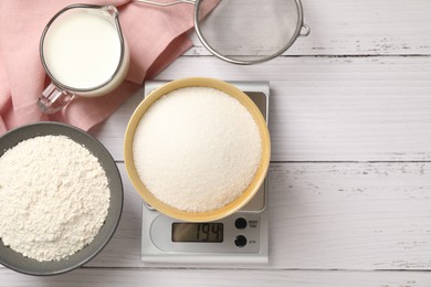 Photo of Digital kitchen scale with bowl of sugar and other products on white wooden table, flat lay. Space for text