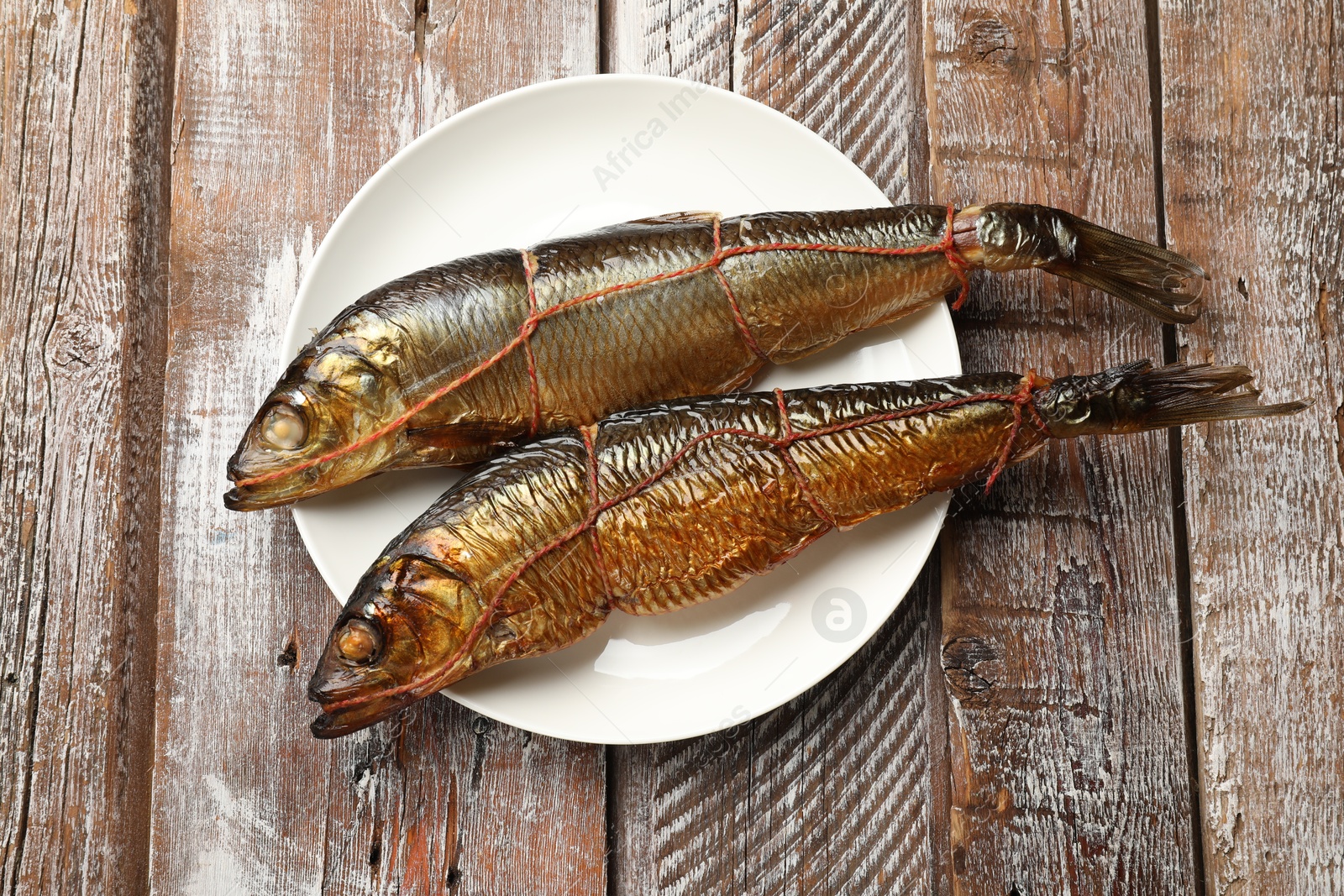 Delicious smoked herrings on wooden table, top view Photo of Delicious smoked herrings on wooden table, top view