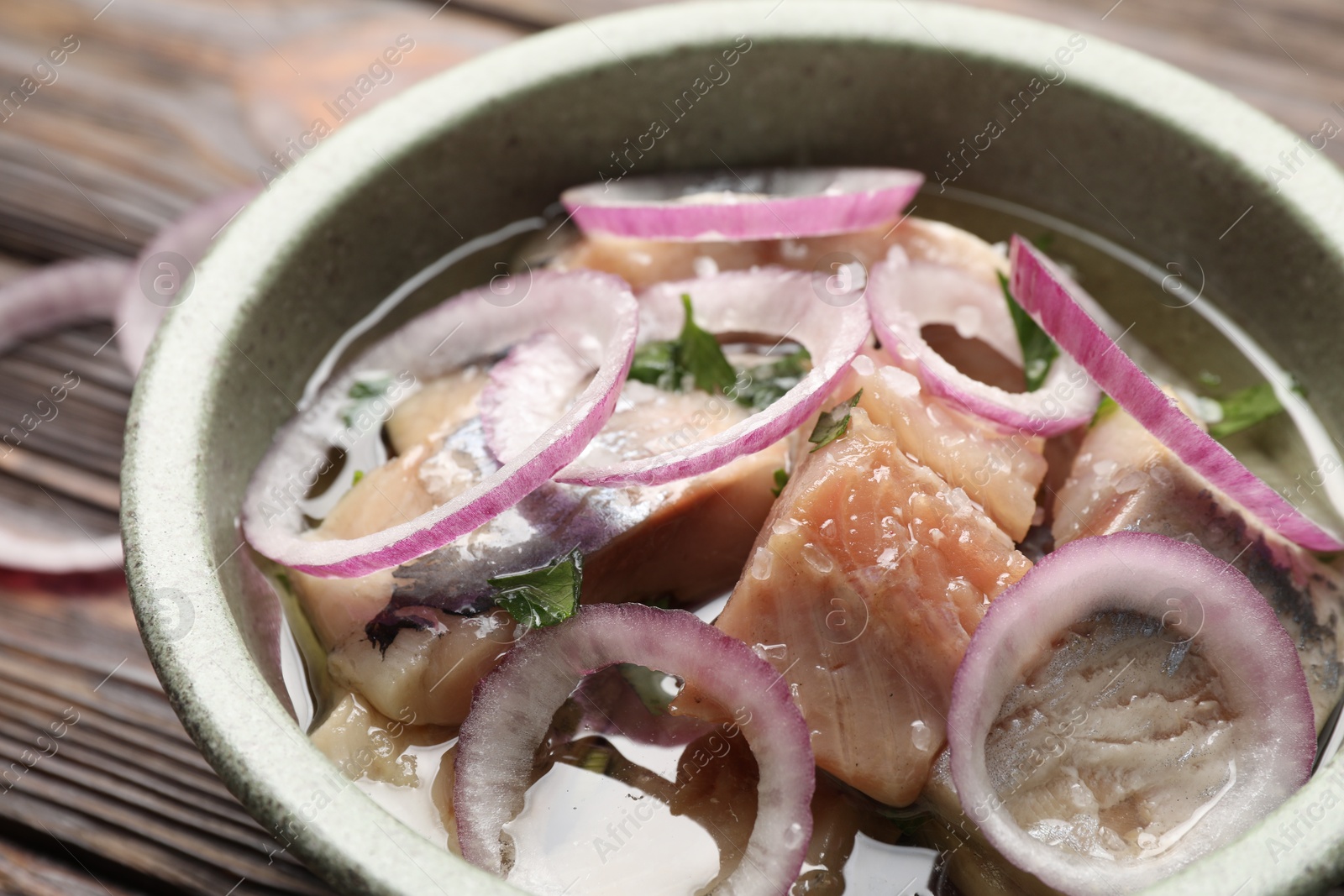 Pieces of delicious herring with onions on wooden table, closeup Photo of Pieces of delicious herring with onions on wooden table, closeup
