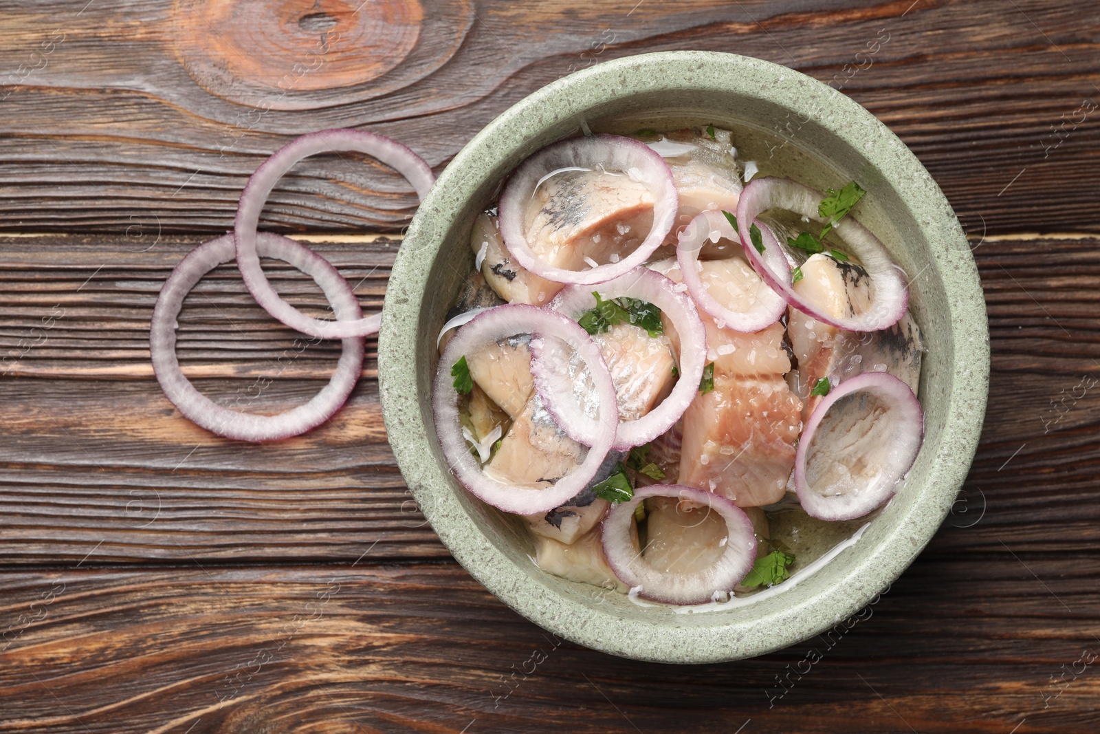 Pieces of delicious herring with onions on wooden table, top view Photo of Pieces of delicious herring with onions on wooden table, top view