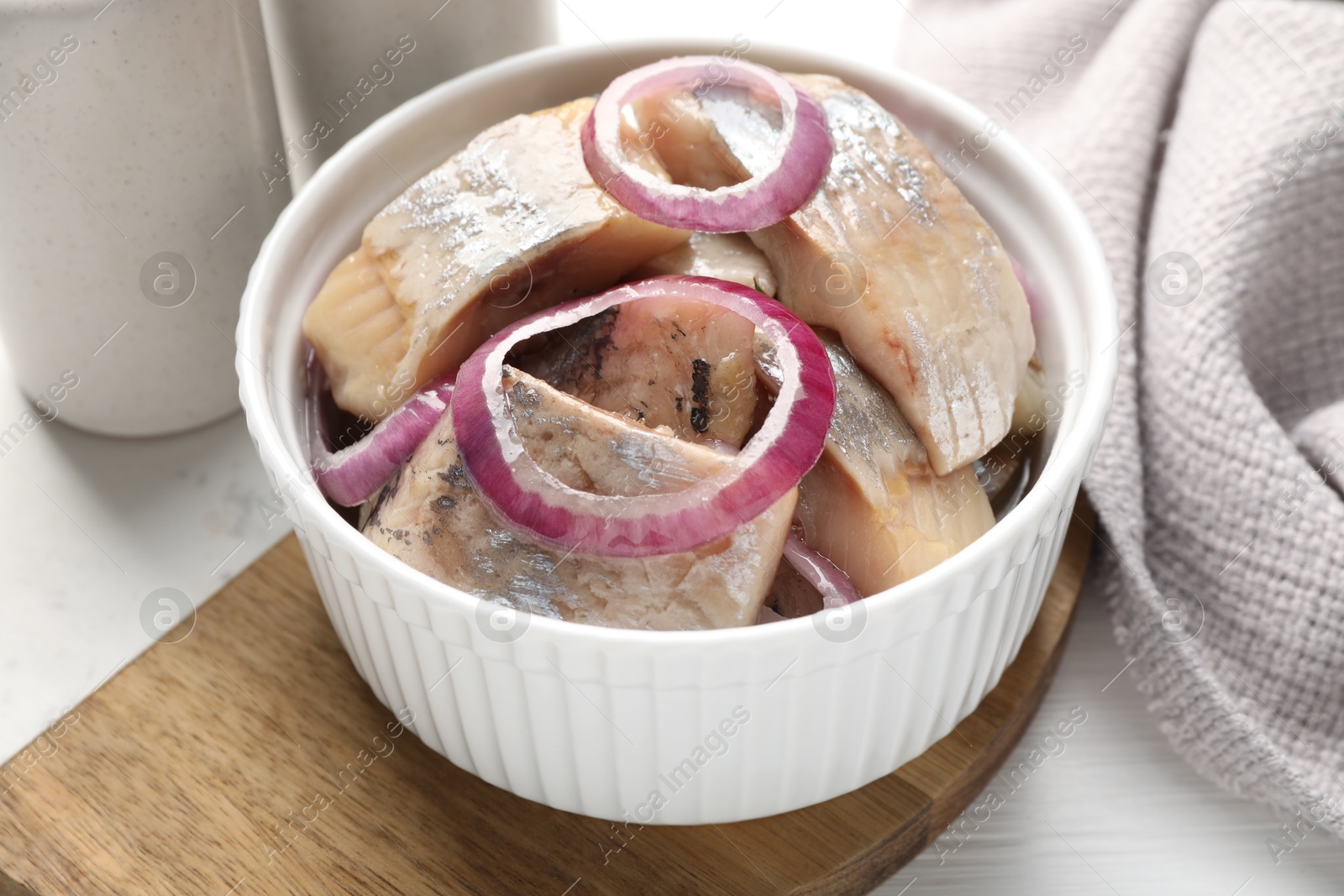 Pieces of delicious herring with onions on white table, closeup Photo of Pieces of delicious herring with onions on white table, closeup
