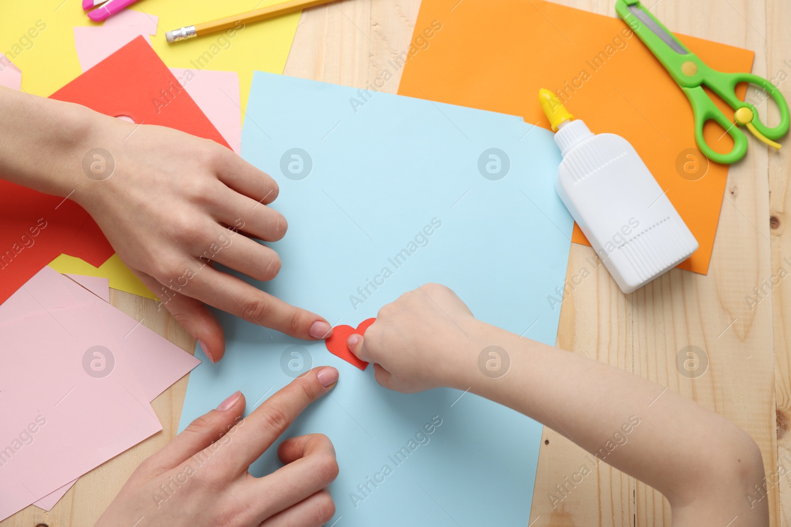 Mother and daughter making handmade greeting card at wooden table, top view Photo of Mother and daughter making handmade greeting card at wooden table, top view