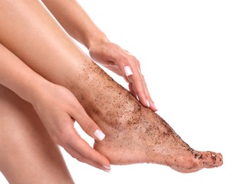 Photo of Woman applying body scrub onto her foot on white background, closeup