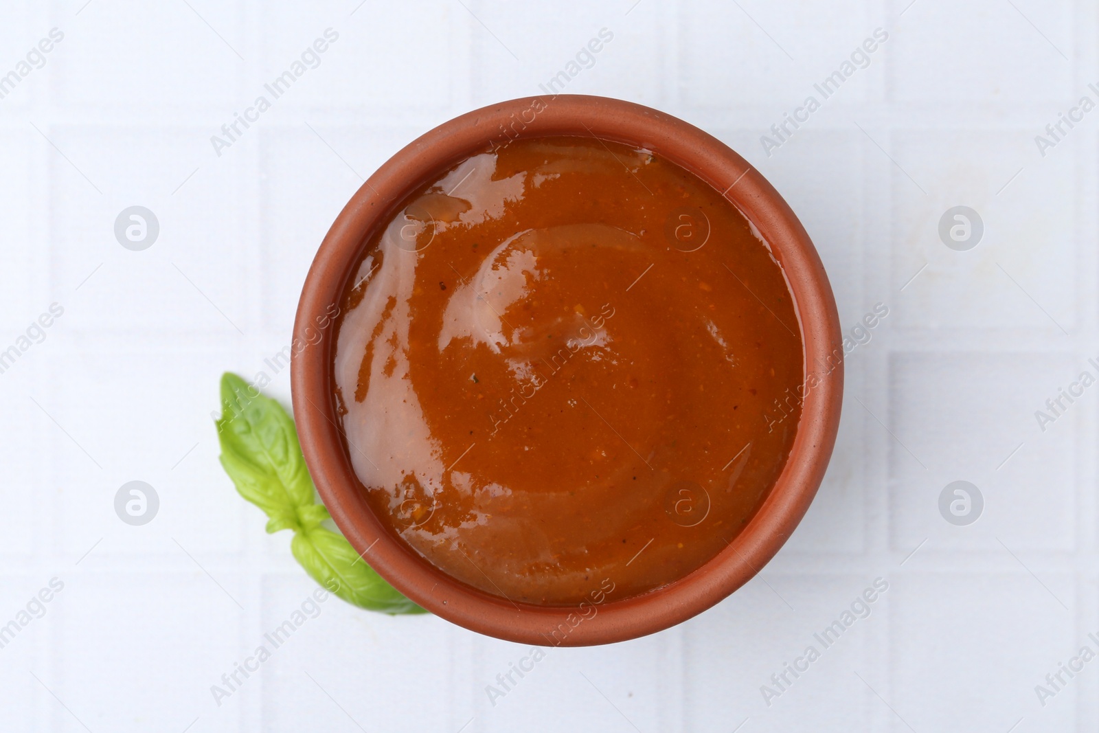 Tasty curry sauce and basil leaves on white tiled table, top view Photo of Tasty curry sauce and basil leaves on white tiled table, top view