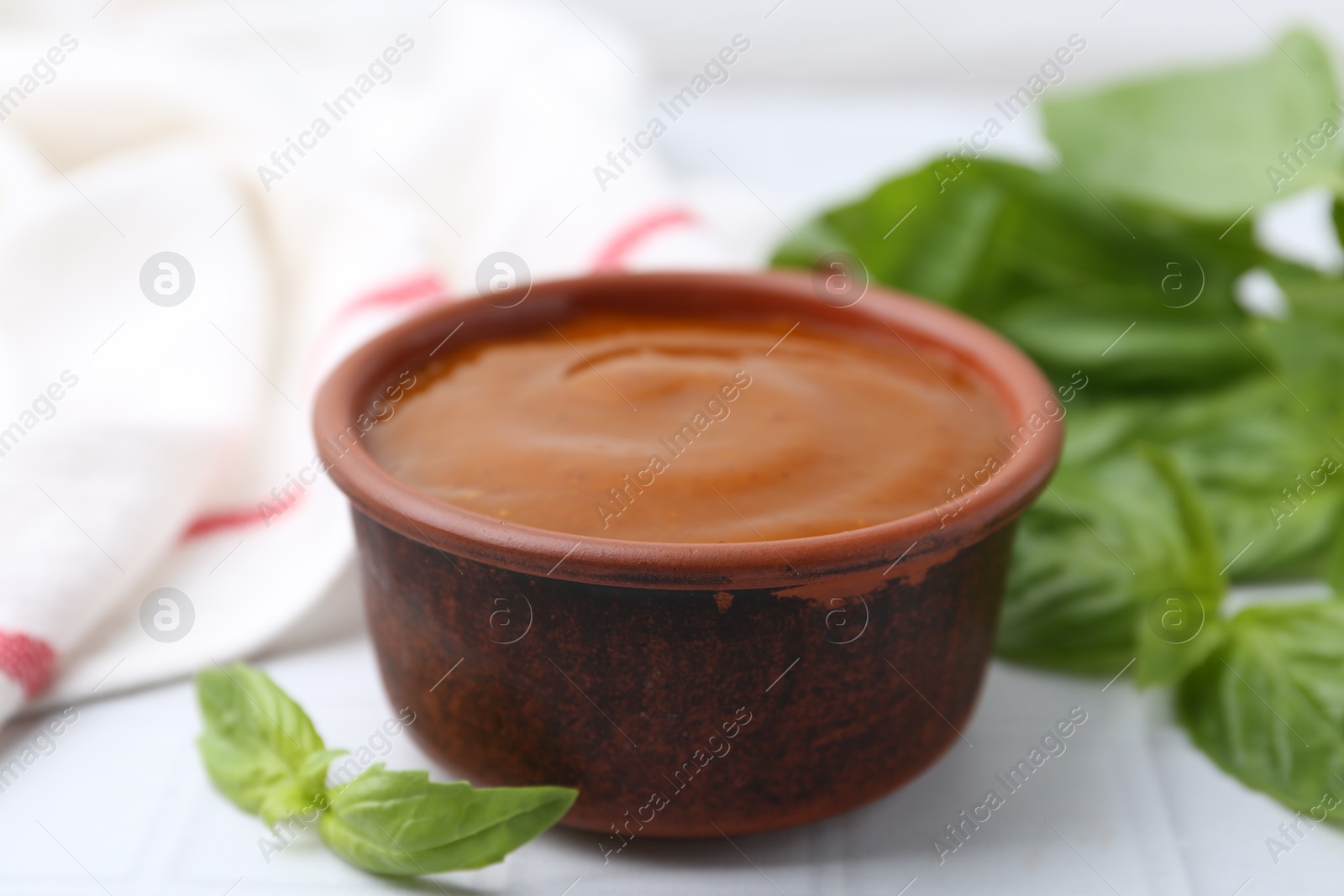 Tasty curry sauce and basil leaves on white tiled table, closeup Photo of Tasty curry sauce and basil leaves on white tiled table, closeup