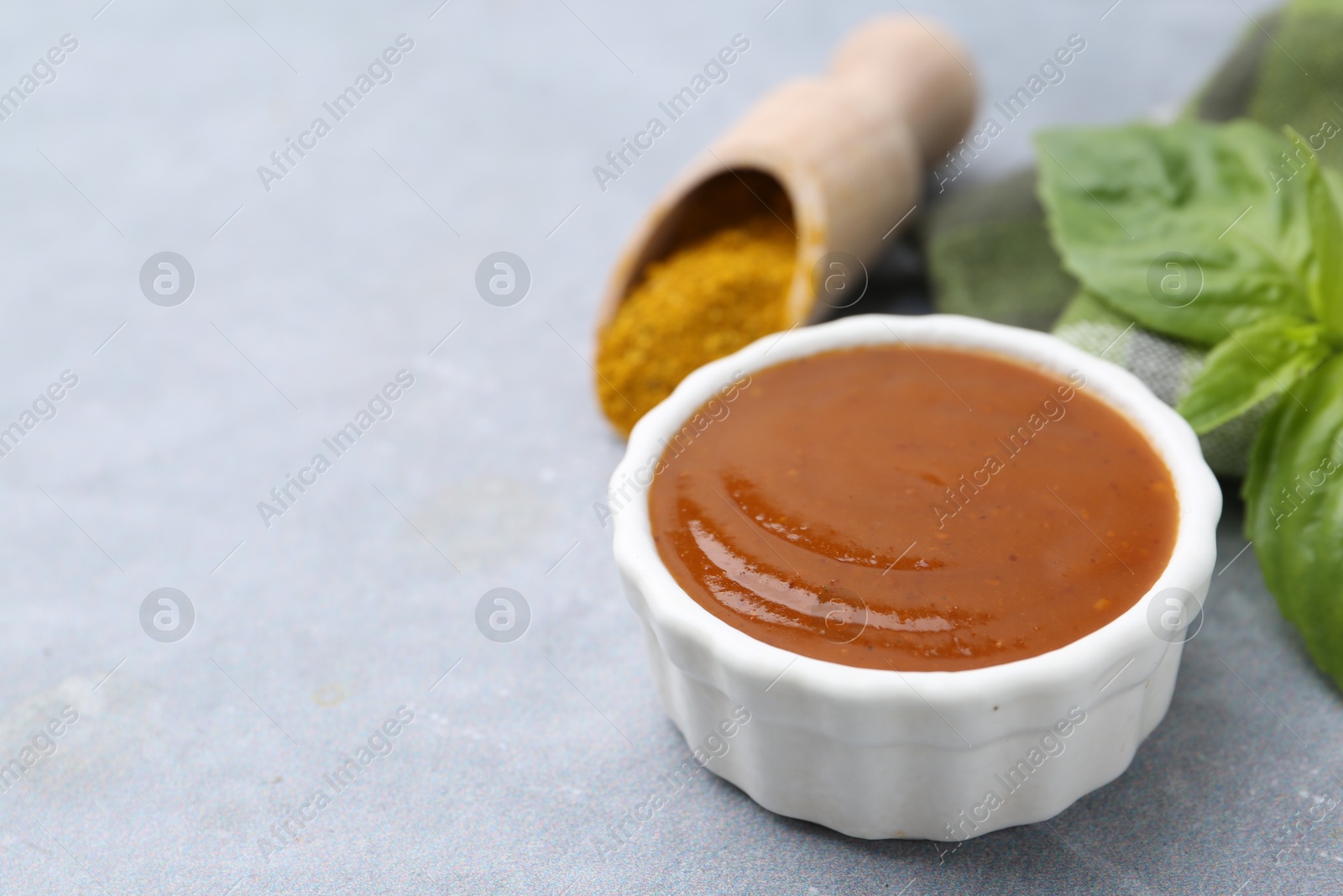 Tasty curry sauce, powder and basil leaves on grey table, closeup. Space for text Photo of Tasty curry sauce, powder and basil leaves on grey table, closeup. Space for text