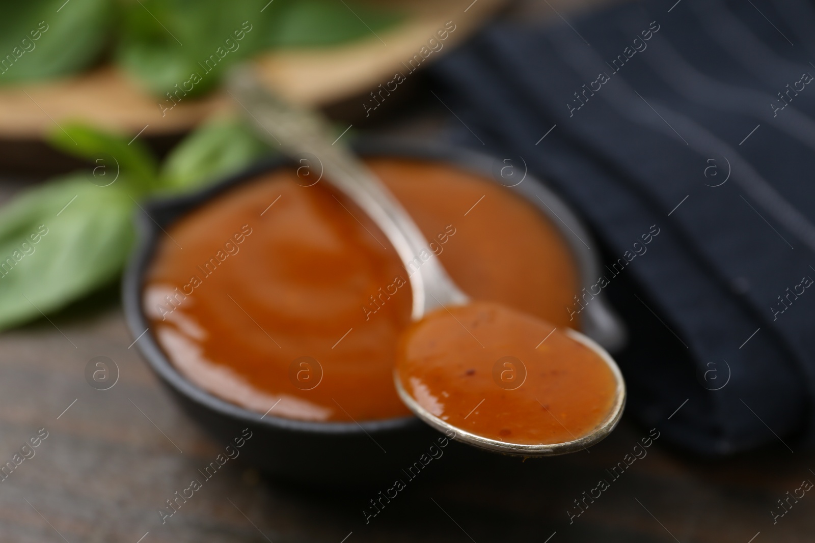 Tasty curry sauce and basil leaves on wooden table, closeup Photo of Tasty curry sauce and basil leaves on wooden table, closeup