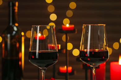 Photo of Glasses of red wine against blurred background, closeup. Romantic dinner
