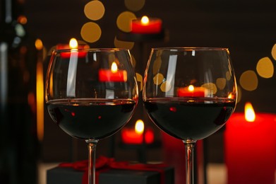 Photo of Glasses of red wine against blurred background, closeup. Romantic dinner