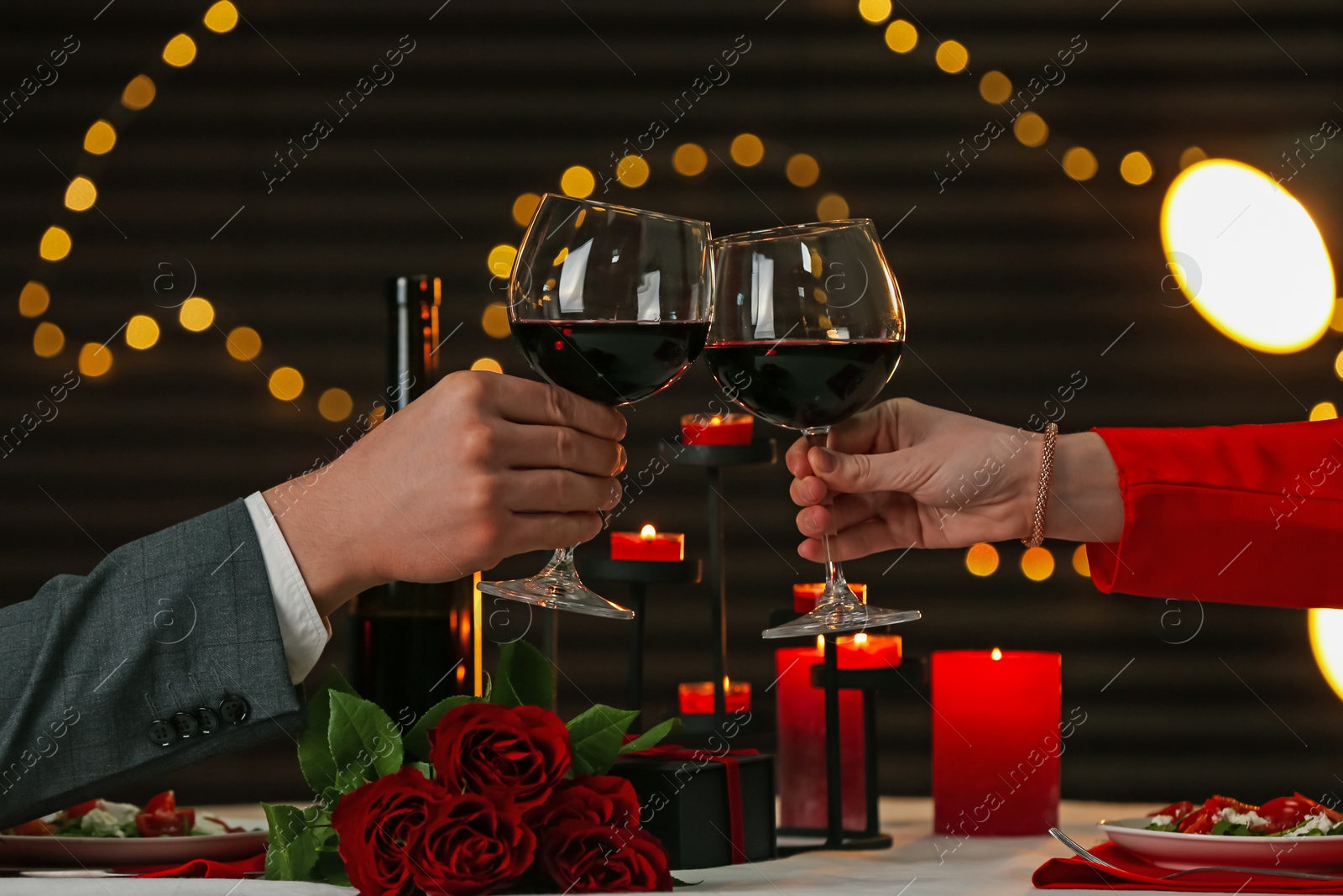 Couple clinking glasses of wine in restaurant, closeup. Romantic dinner Photo of Couple clinking glasses of wine in restaurant, closeup. Romantic dinner
