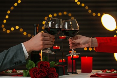 Photo of Couple clinking glasses of wine in restaurant, closeup. Romantic dinner