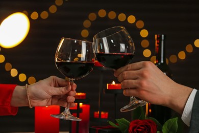 Photo of Couple clinking glasses of wine in restaurant, closeup. Romantic dinner