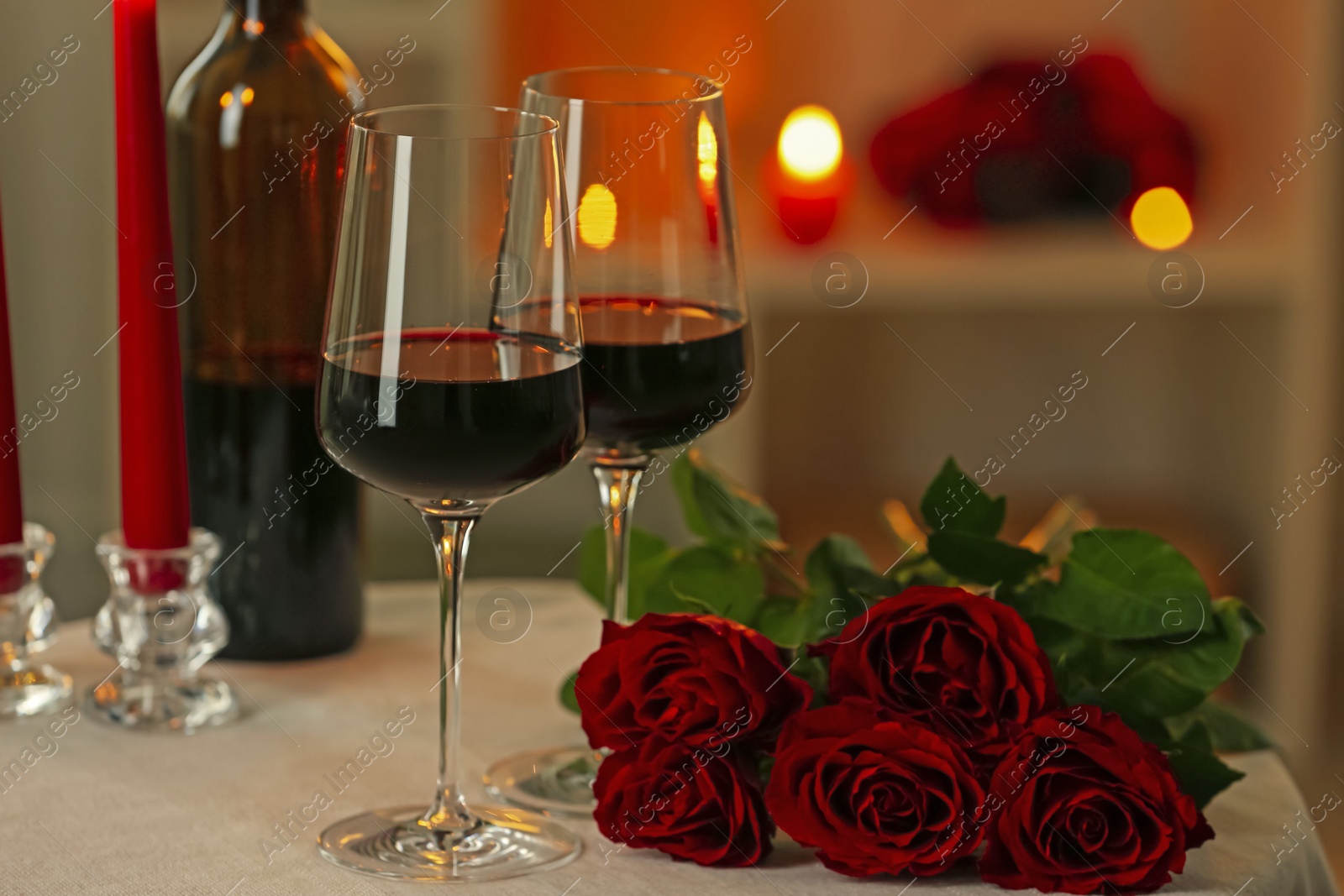 Photo of Glasses of red wine and roses on table in restaurant. Romantic dinner
