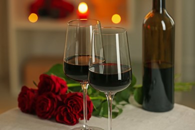 Photo of Glasses of red wine and roses on table in restaurant. Romantic dinner
