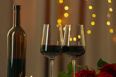 Photo of Glasses of red wine against blurred lights, closeup. Romantic dinner