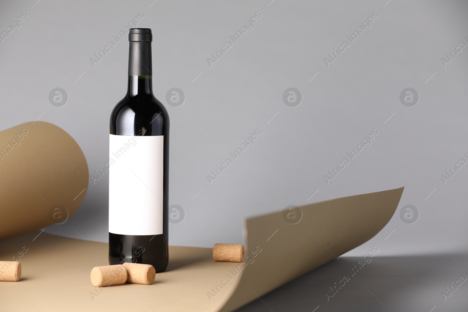 Photo of Bottle of wine with corks and paper on grey background. Space for text