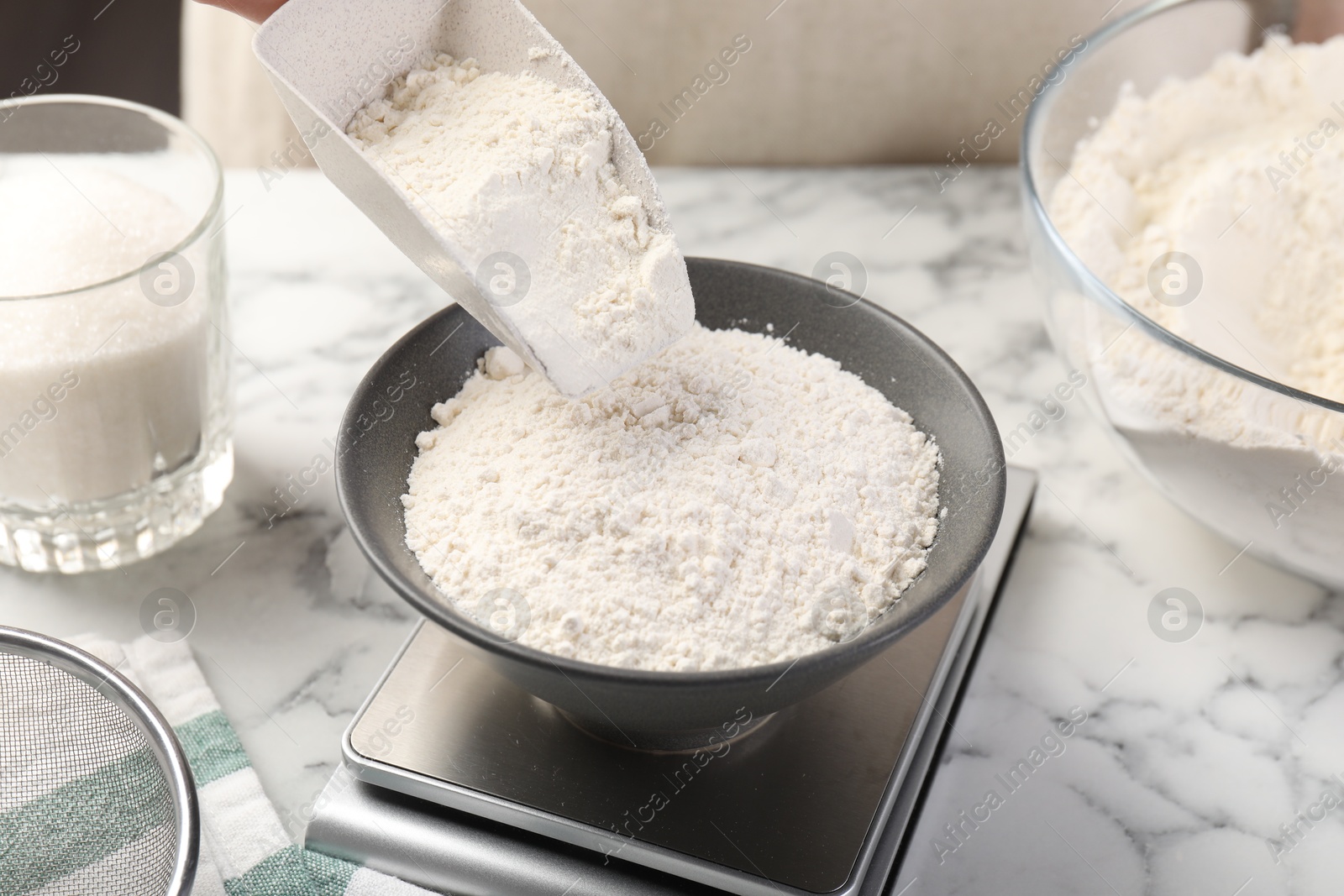 Woman putting sugar into bowl on digital kitchen scale at white marble table, closeup Photo of Woman putting sugar into bowl on digital kitchen scale at white marble table, closeup