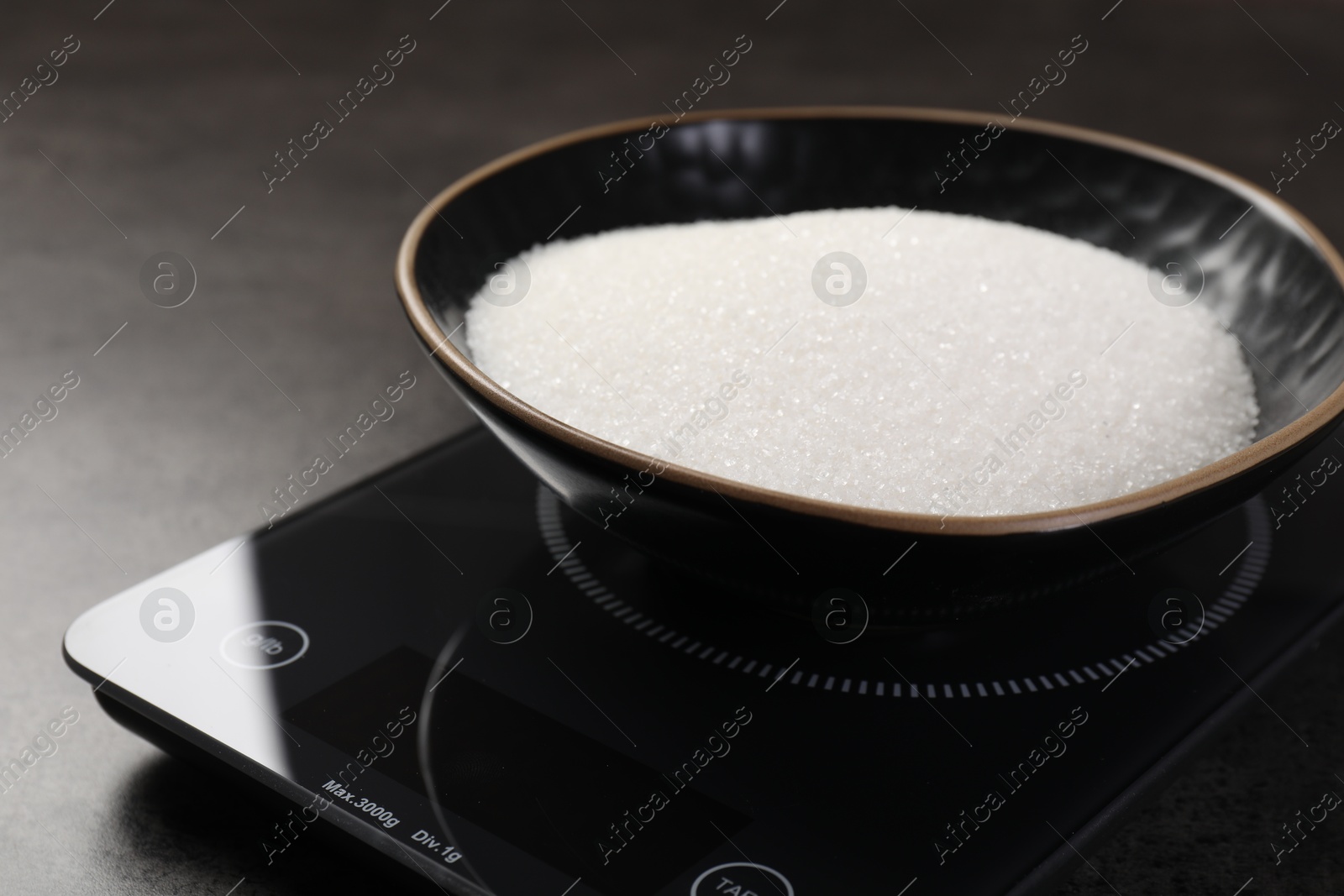 Digital kitchen scale with bowl of sugar on grey table, closeup Photo of Digital kitchen scale with bowl of sugar on grey table, closeup