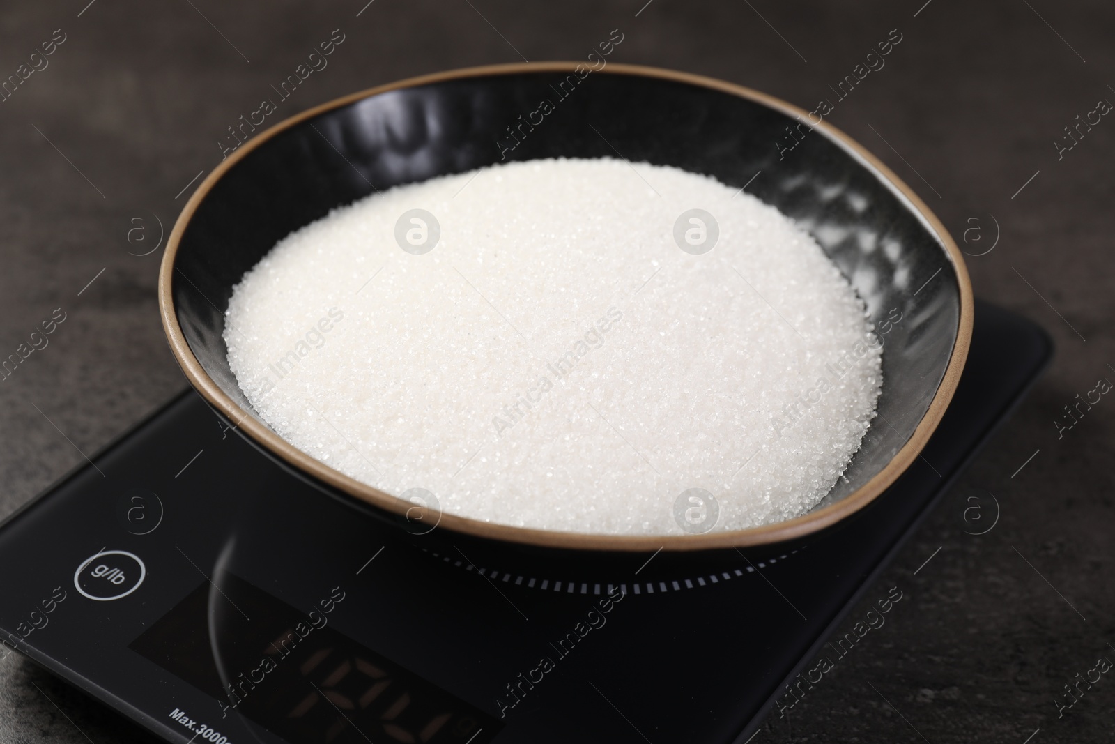 Digital kitchen scale with bowl of sugar on grey table, closeup Photo of Digital kitchen scale with bowl of sugar on grey table, closeup