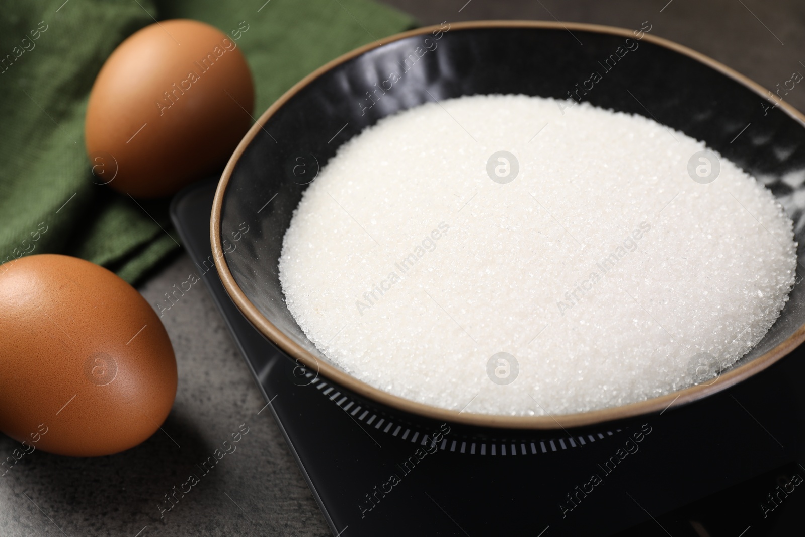 Digital kitchen scale with bowl of sugar and other products on grey table, closeup Photo of Digital kitchen scale with bowl of sugar and other products on grey table, closeup