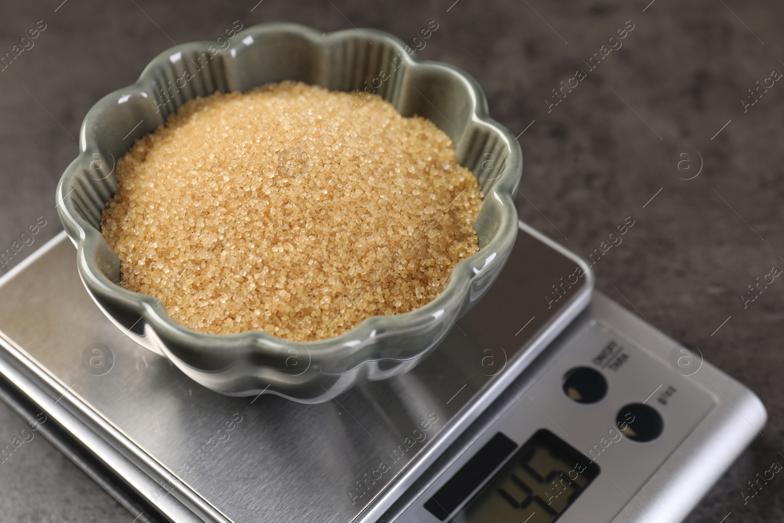 Digital kitchen scale with bowl of brown sugar on grey table, closeup Photo of Digital kitchen scale with bowl of brown sugar on grey table, closeup