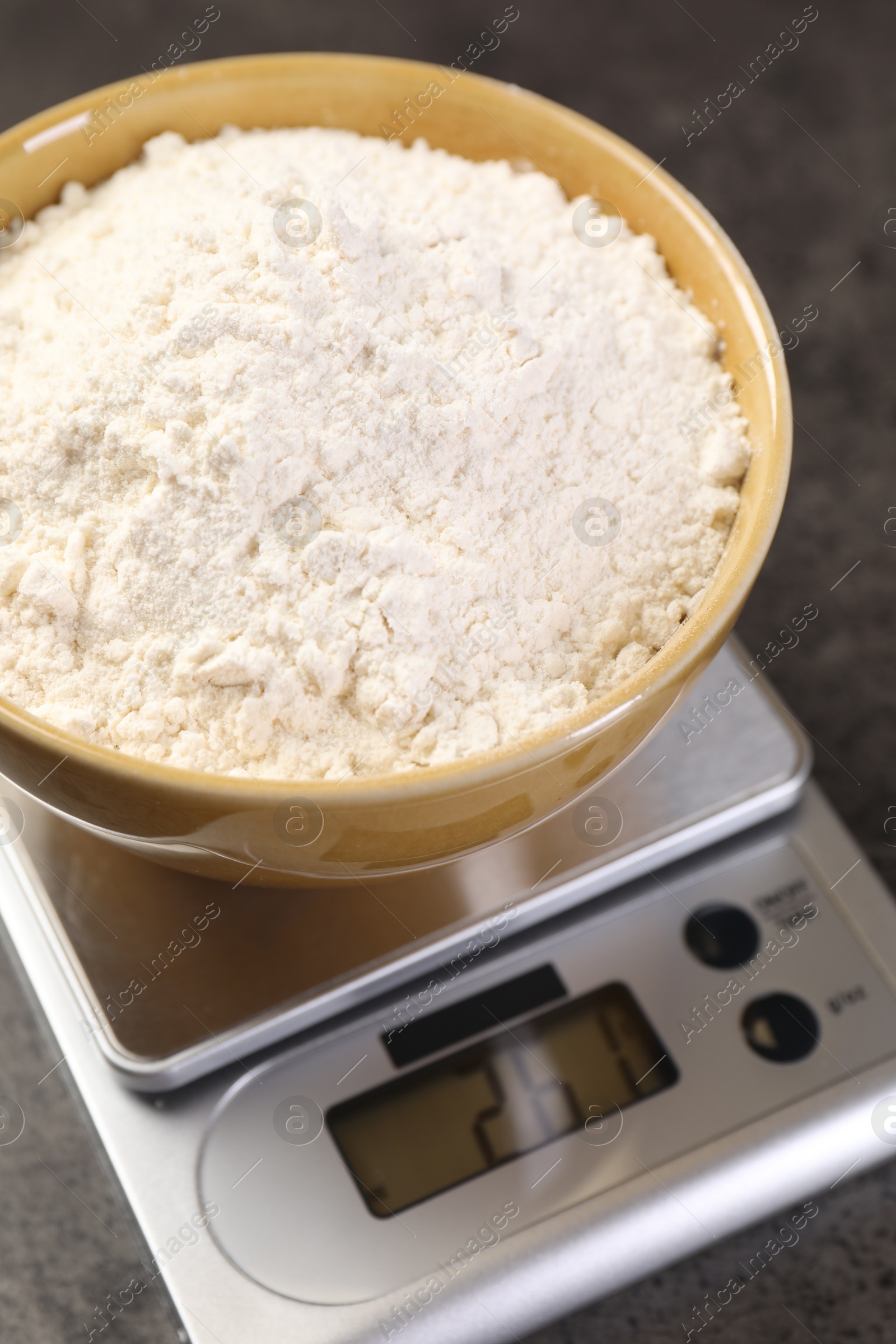 Digital kitchen scale with bowl of flour on grey table, closeup Photo of Digital kitchen scale with bowl of flour on grey table, closeup