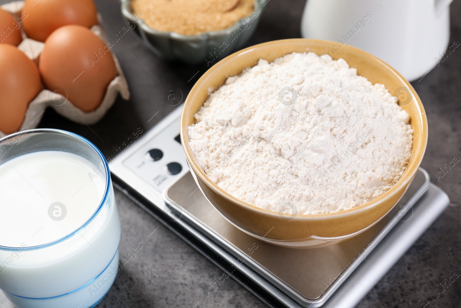 Digital kitchen scale with bowl of flour and other products on grey table, closeup Photo of Digital kitchen scale with bowl of flour and other products on grey table, closeup
