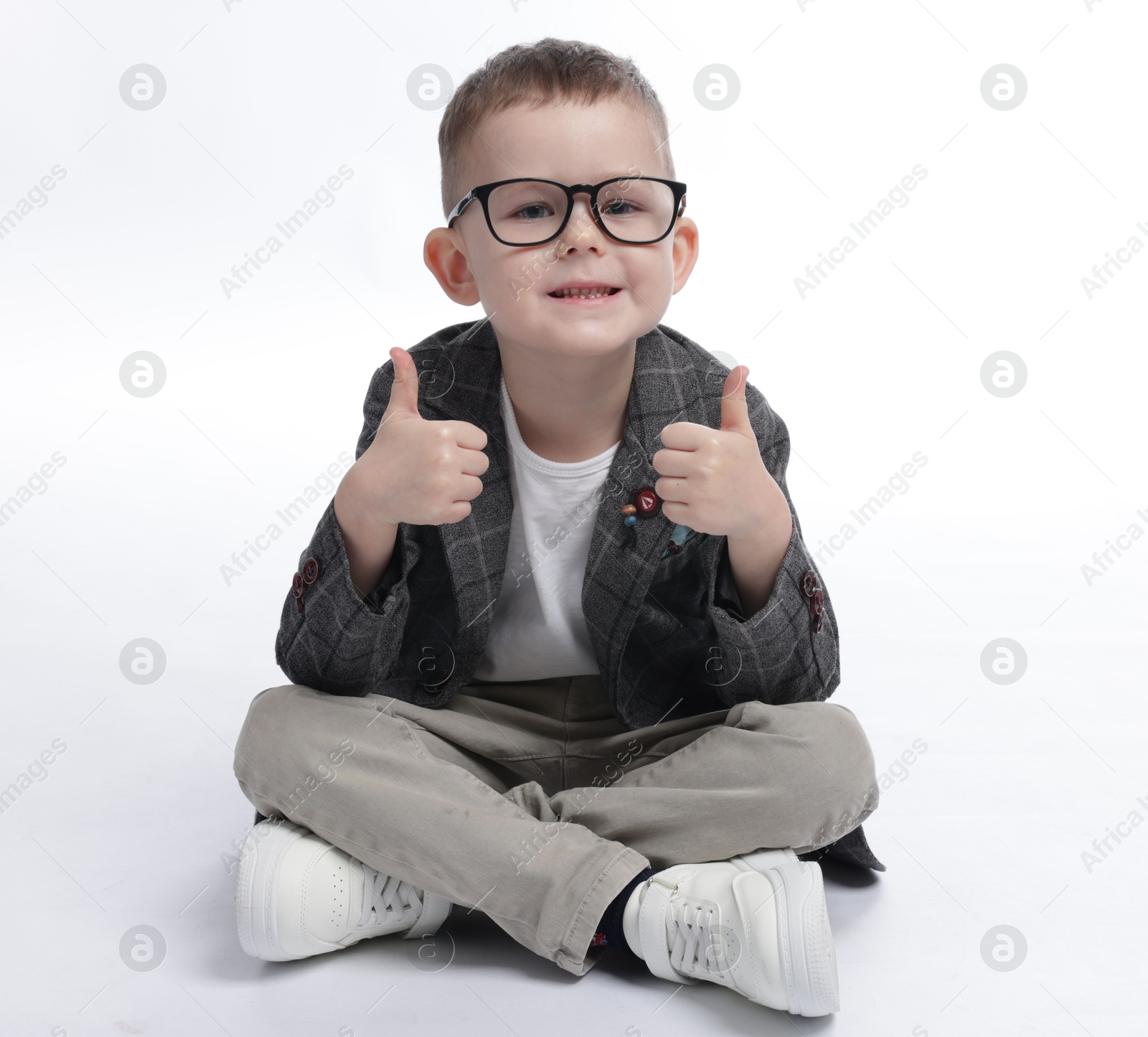 Cute little boy in glasses showing thumbs up on white background Photo of Cute little boy in glasses showing thumbs up on white background