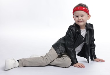 Photo of Cute little boy in black leather jacket on white background