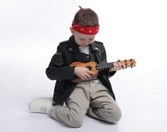 Photo of Cute little boy playing toy guitar on white background