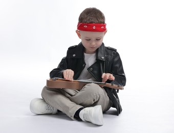Photo of Cute little boy playing toy guitar on white background