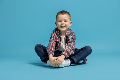 Photo of Cute little boy in checkered shirt on light blue background